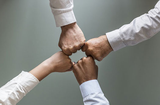 Cuatro personas unen sus manos como símbolo de colaboración